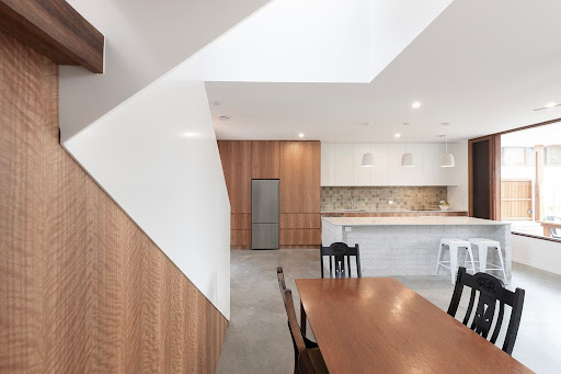 Modern kitchen and dining area with white walls and timber cabinetry
