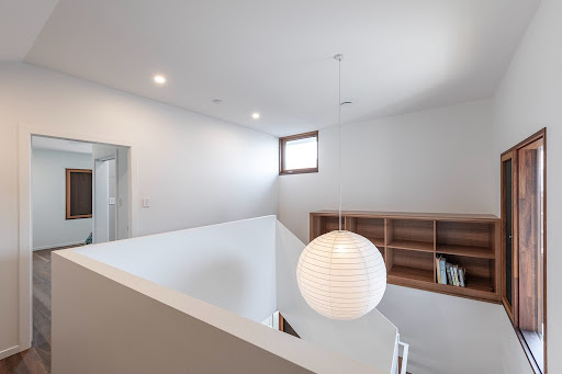 Upper landing with crisp white walls, pendant light and built-in timber shelving