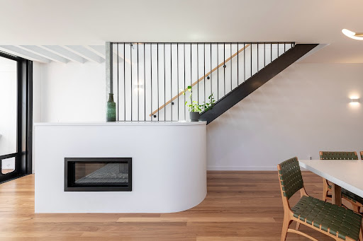 Interior living area with white feature wall, built-in fireplace and black staircase