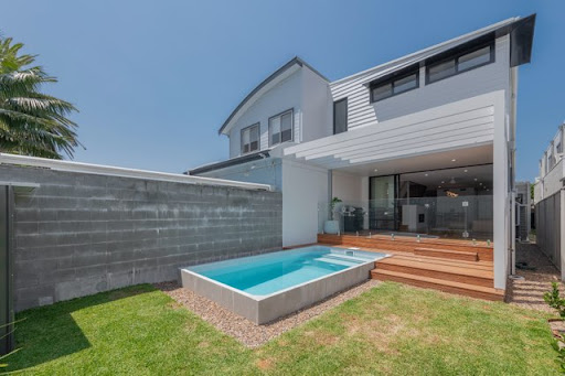 Exterior of white rendered home with dark trim, pool and timber deck